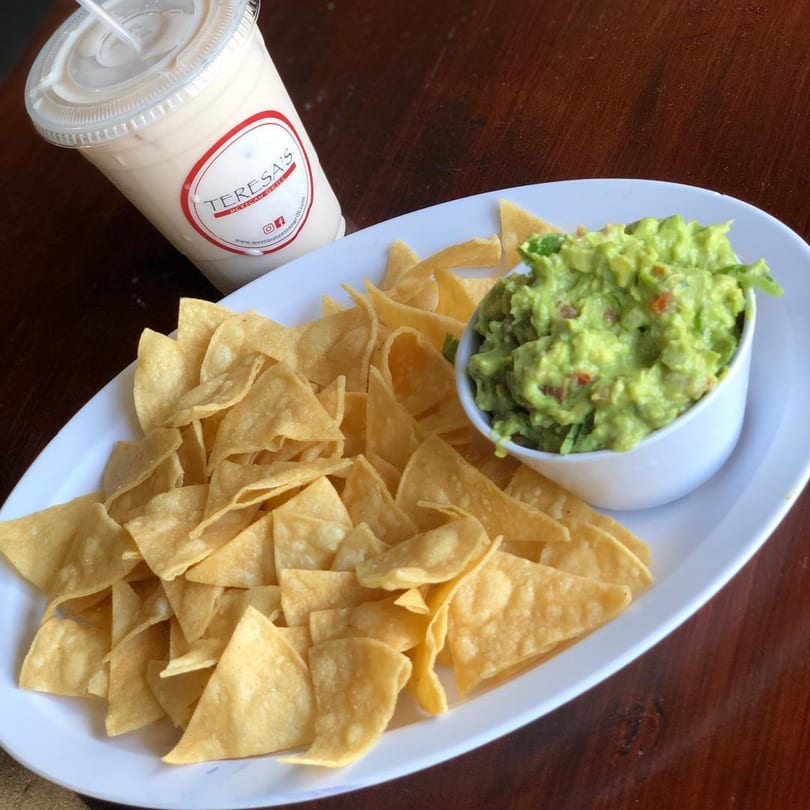 Teresa's Mexican Grill's guacamole and tortilla chips on a white plate with a drink.